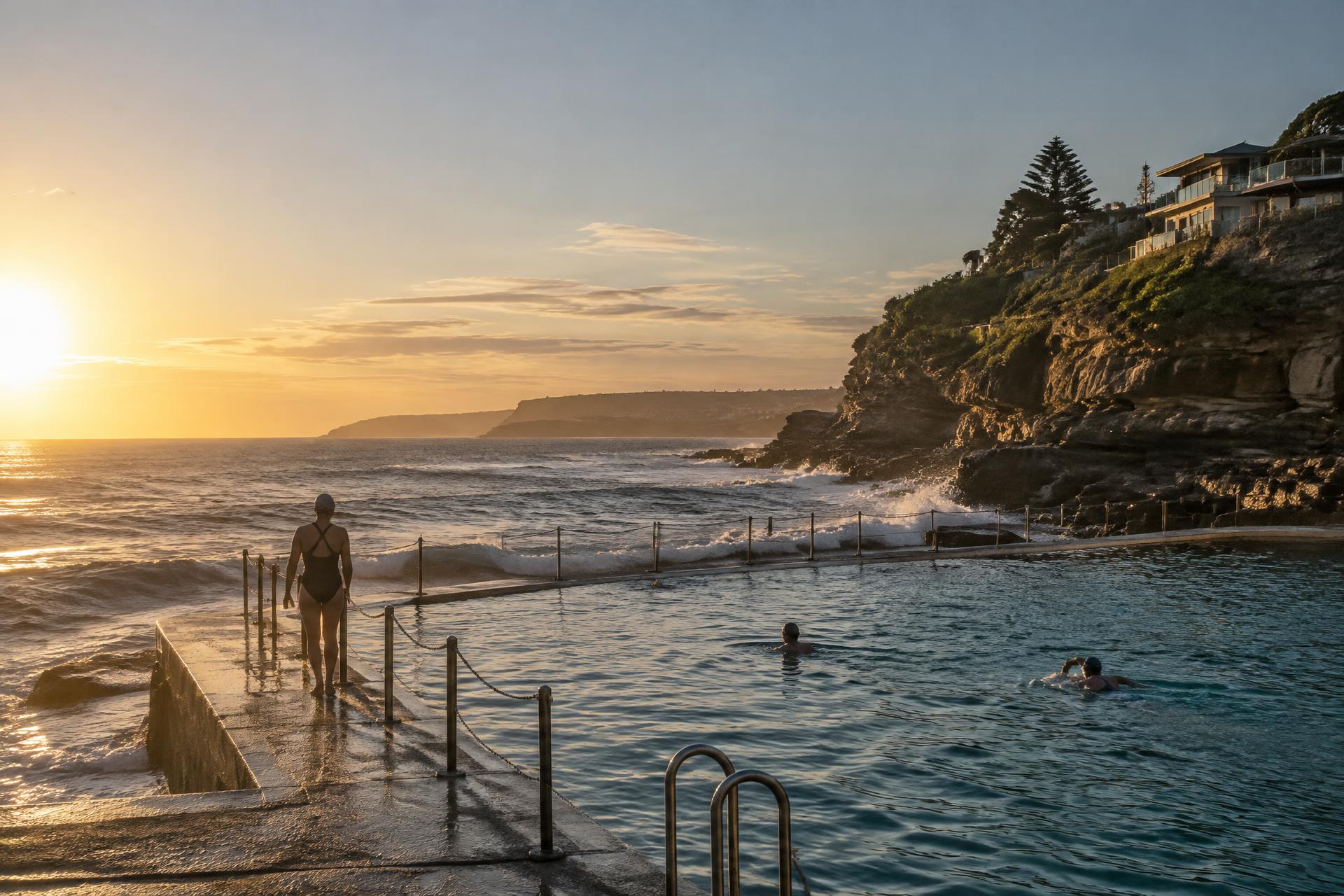 Swimmers at an ocean pool on the New South Wales coast at sunrise